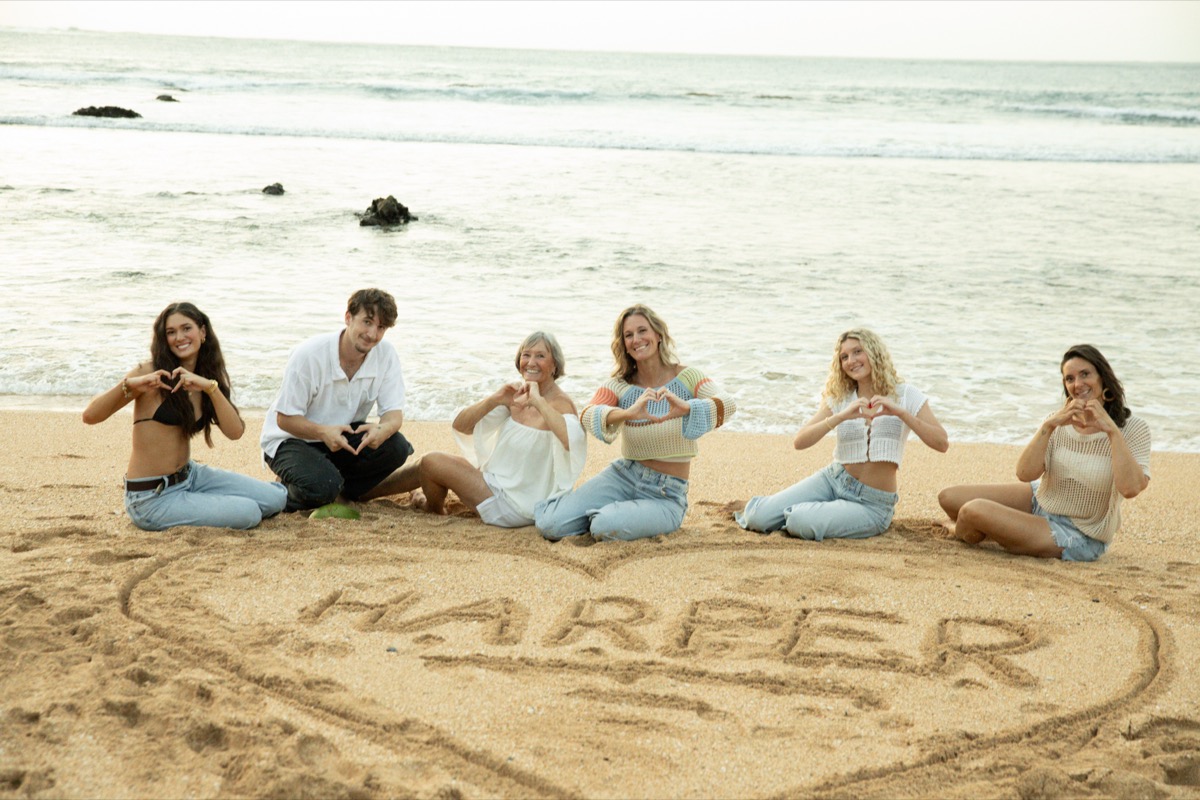 Family around HARPER written in the sand